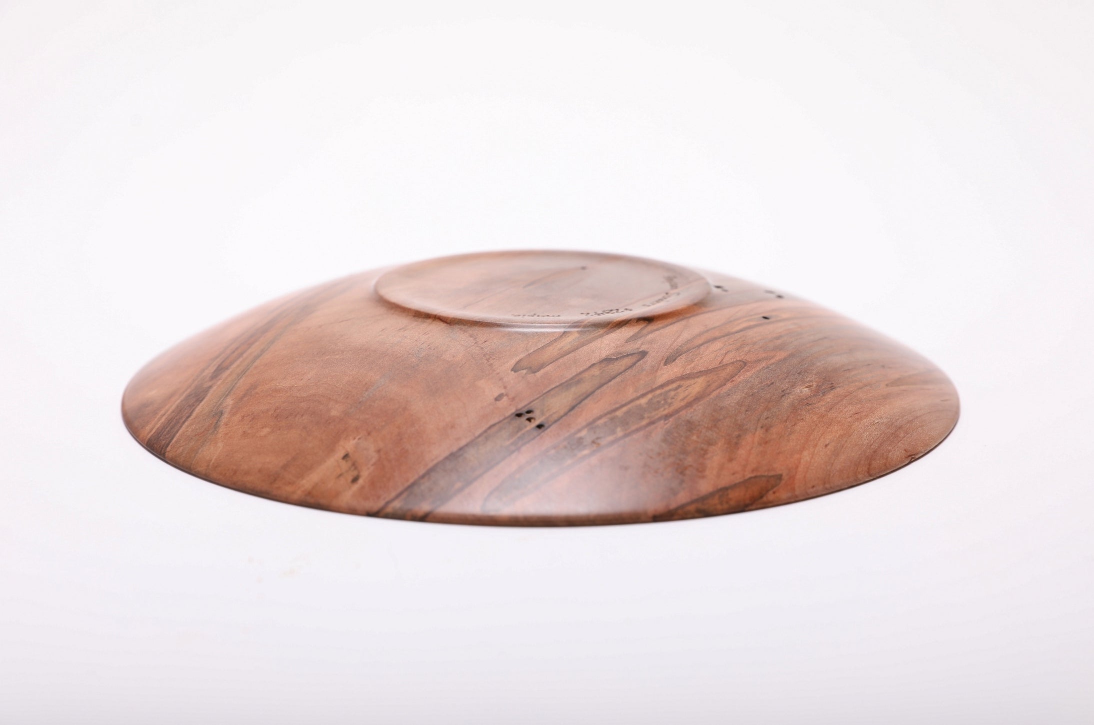 Bottom view of hand-turned ambrosia maple shallow dish showing raised foot and repaired drying crack with natural oil finish