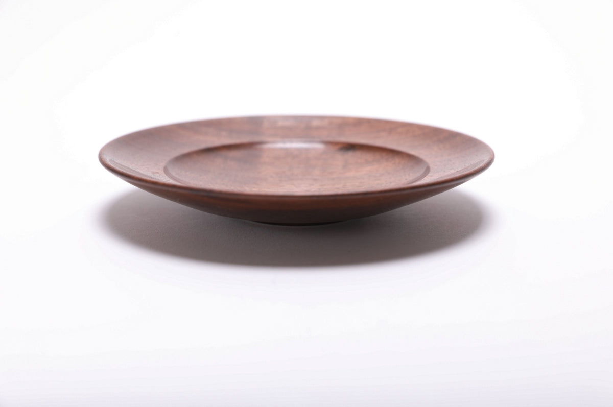 Side profile of hand-turned quartersawn black walnut ring dish showing low curved profile, raised foot, and undercut rim