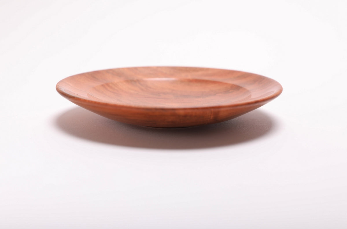 Side profile of hand-turned wild black cherry burl ring dish showing low curved taper, raised foot, and warm pink-orange grain
