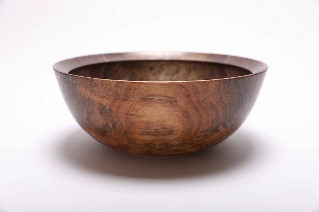Side profile of hand-turned spalted wild black walnut bowl showing deep curved form, raised foot, and warm brown exterior grain