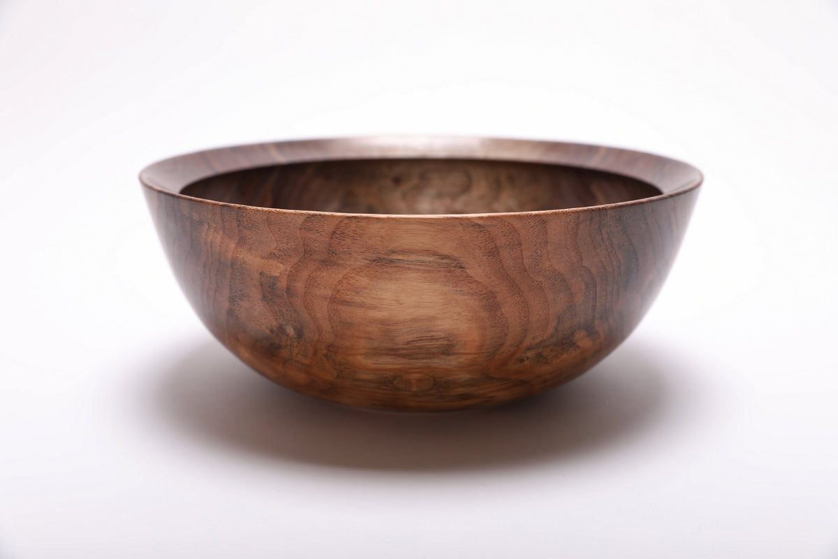 Side profile of hand-turned spalted wild black walnut bowl showing deep curved form, raised foot, and warm brown exterior grain