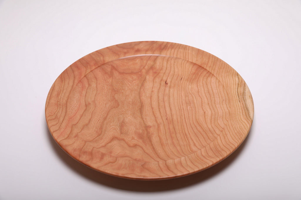 Top view of curly wild black cherry platter highlighting flowing curly grain pattern and warm rose-pink tones with natural oil finish