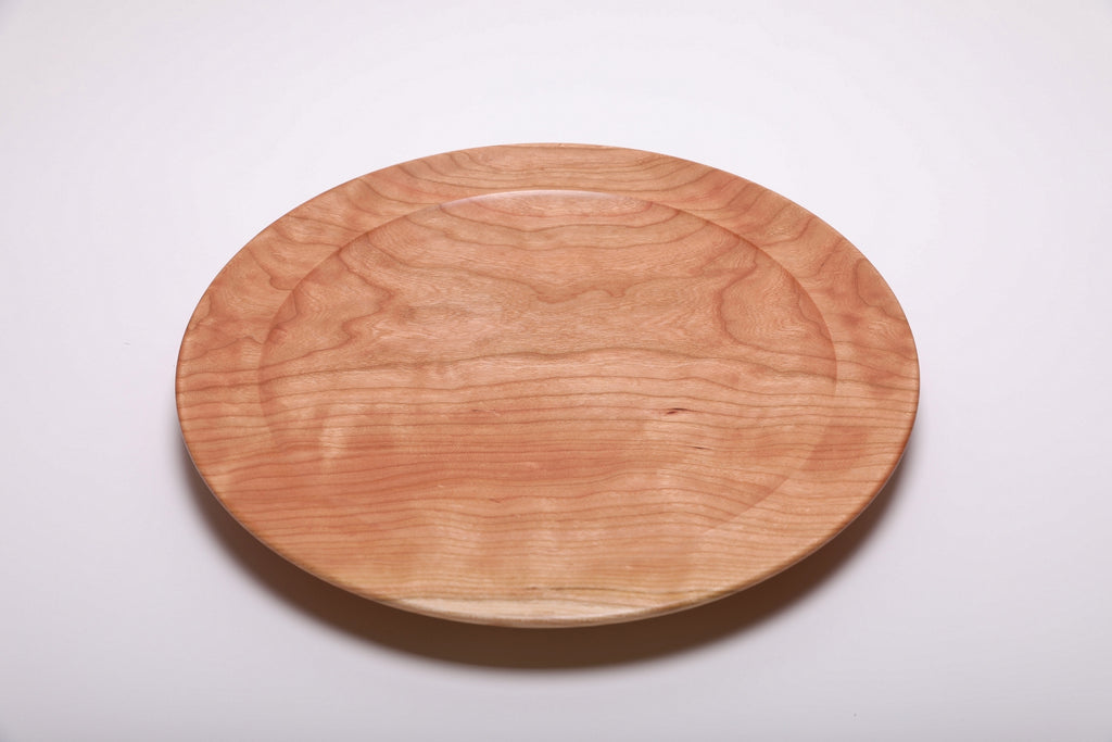 Top view of handmade curly wild black cherry platter showing warm salmon grain with curly figure and undercut rim detail