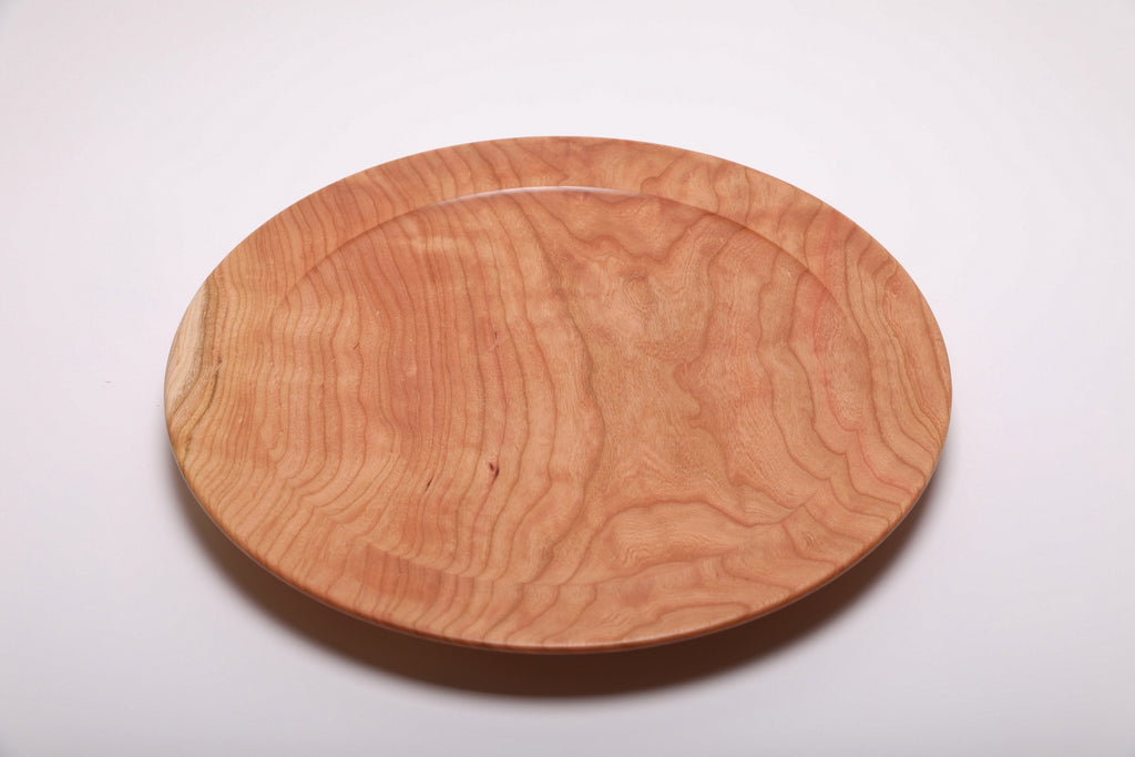 Top view of hand-turned curly wild black cherry platter with pronounced curly grain and soft pink-orange cherry tones across the full surface