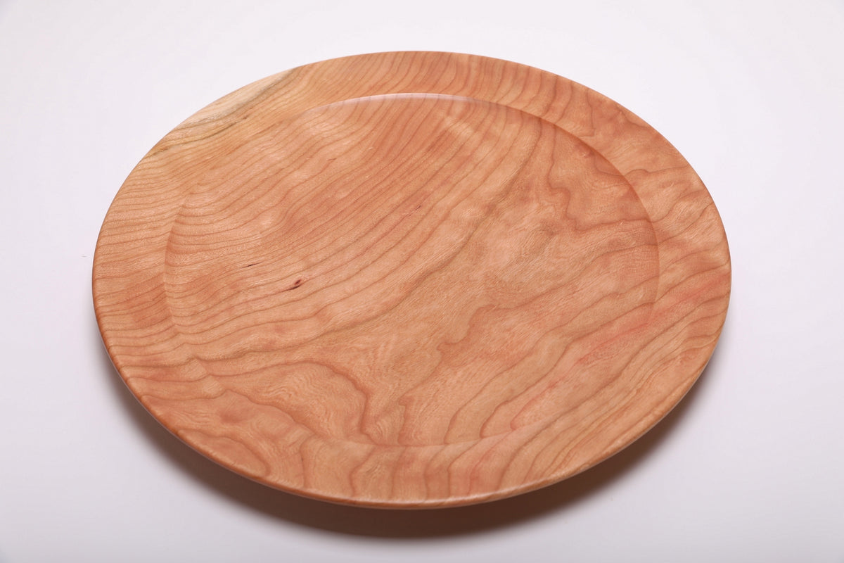 Top view of hand-turned curly wild black cherry wooden platter showing flowing curly grain and warm salmon-pink tones with undercut rim, 15 inches