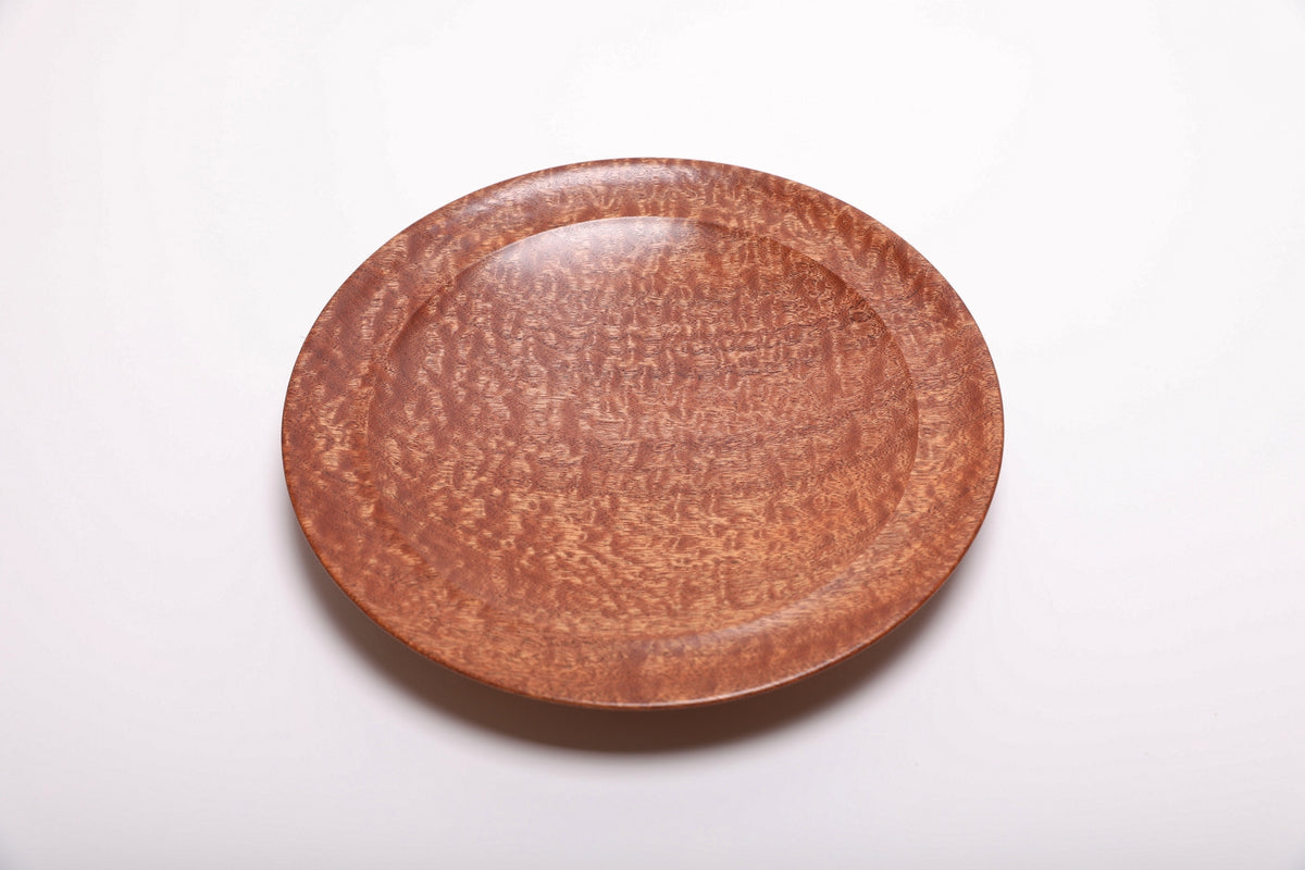 Top view of hand-turned pommele sapele wooden bowl showing dense chatoyant dapple figure and rich mahogany tones with undercut rim, 10 inches