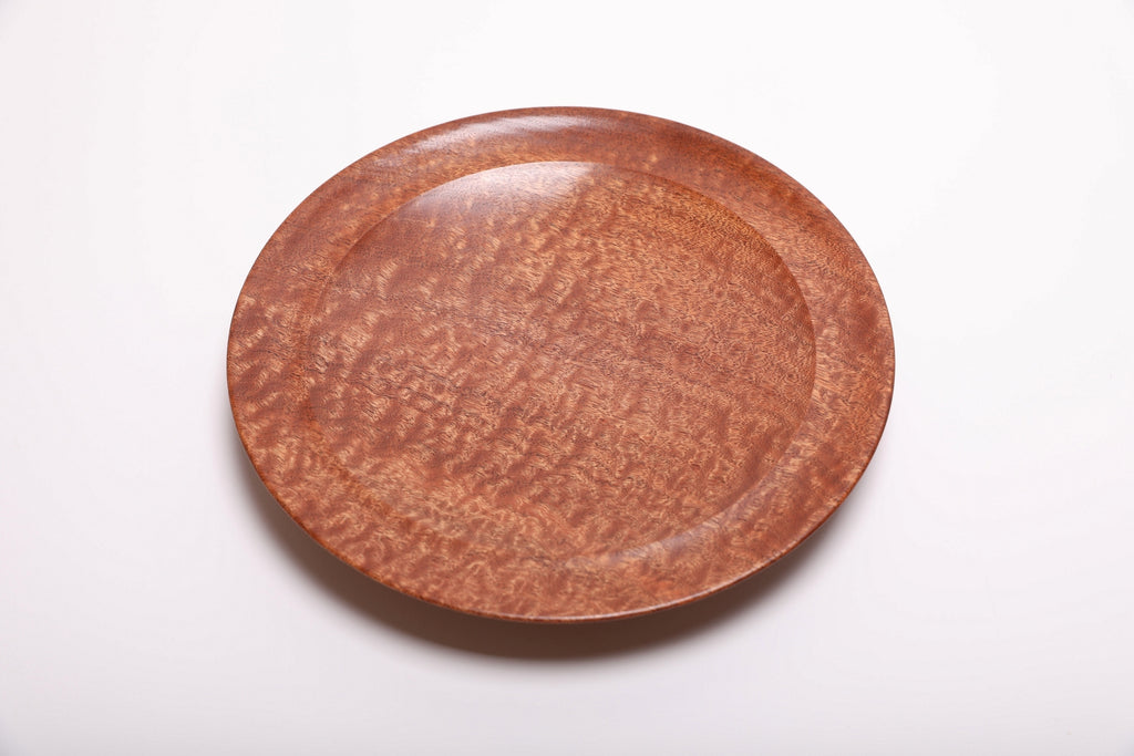 Top view of hand-turned pommele sapele wooden bowl showing shifting chatoyant dapple figure and warm mahogany tones across the full surface