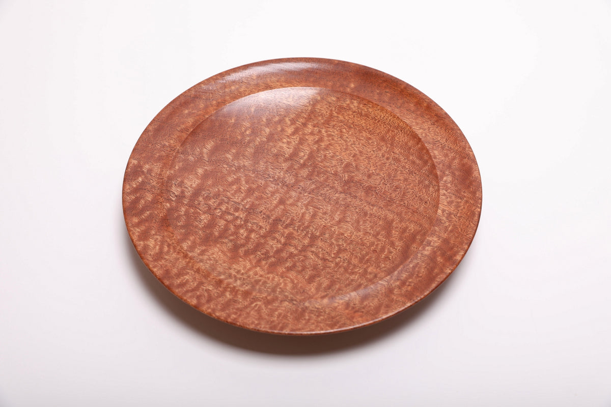 Top view of hand-turned pommele sapele wooden bowl showing shifting chatoyant dapple figure and warm mahogany tones across the full surface