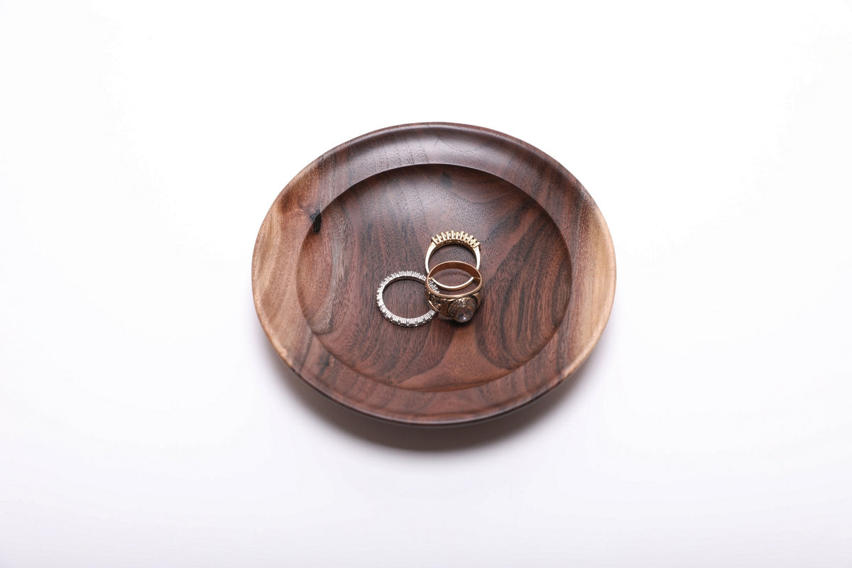 Three gold rings resting in a hand-turned wild black walnut jewelry dish for scale, top view, 4 7/8 inch diameter