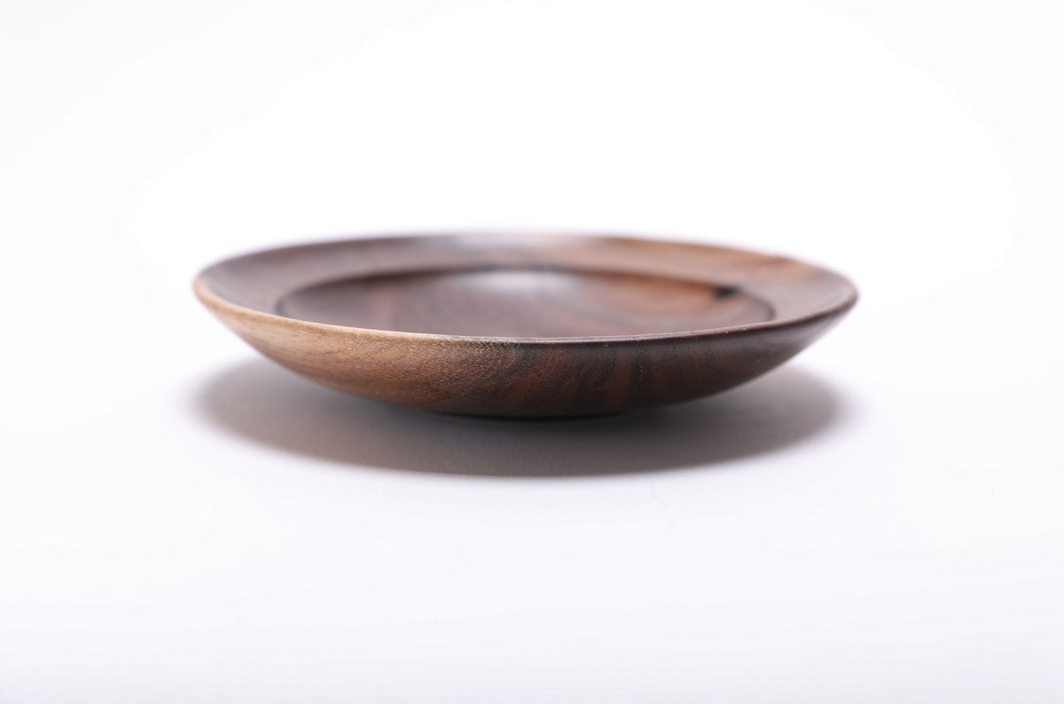 Side profile of hand-turned wild black walnut ring dish showing shallow curved form, raised foot, and sapwood edge detail, 7/8 inch height