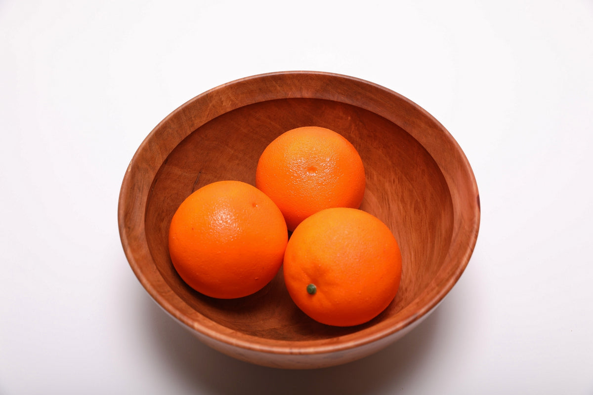 Bradford pear wooden bowl holding three oranges, showing reddish-brown wood and ambrosia streaks