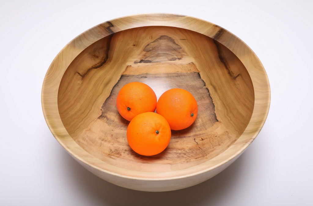 Top view of the rainbow tulip poplar bowl holding three oranges