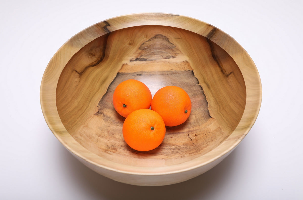 Top view of the rainbow tulip poplar bowl holding three oranges