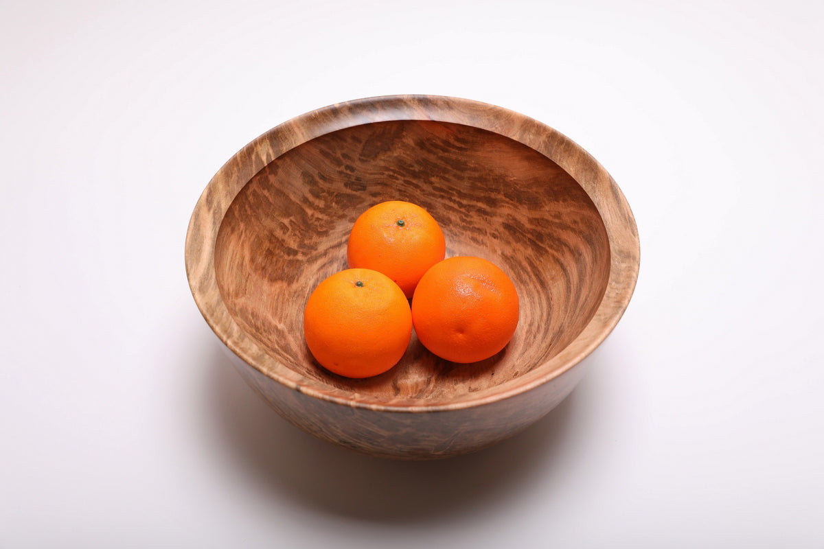 Spalted ambrosia maple fruit bowl holding three oranges, with its patterned interior visible