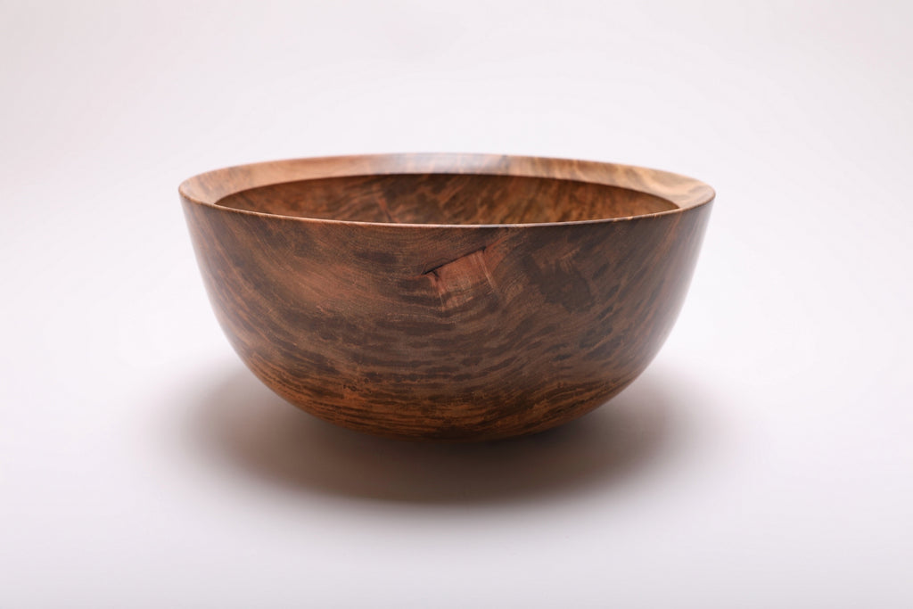 Side view of the ambrosia maple bowl with dark sweeping grain and a small natural wood marking