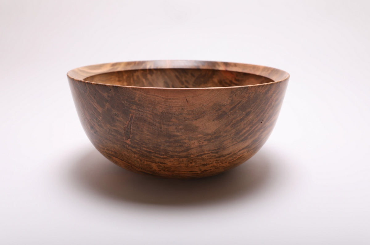 Side view of the maple bowl showing broad brown grain bands and its gently tapered profile