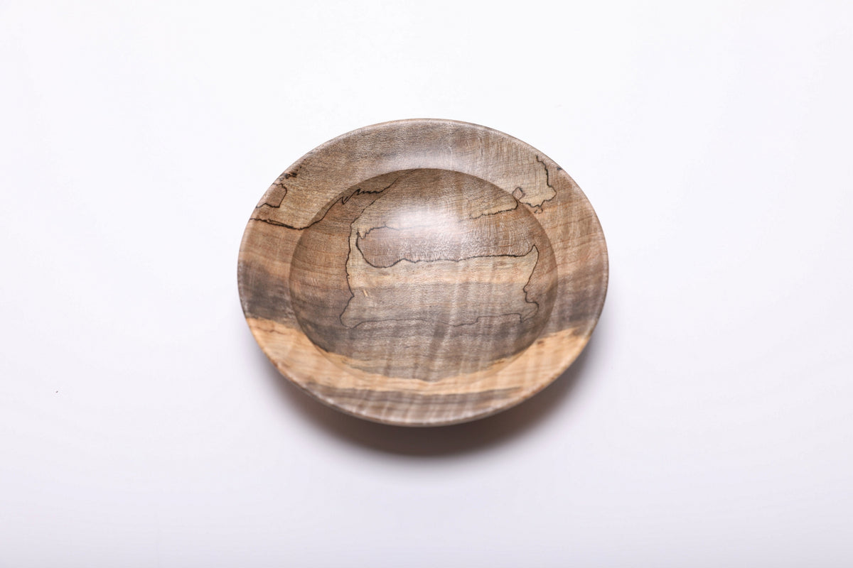 Spalted tiger maple ring dish viewed from above, with fine black lines, gray-brown grain and a golden band across the near rim.