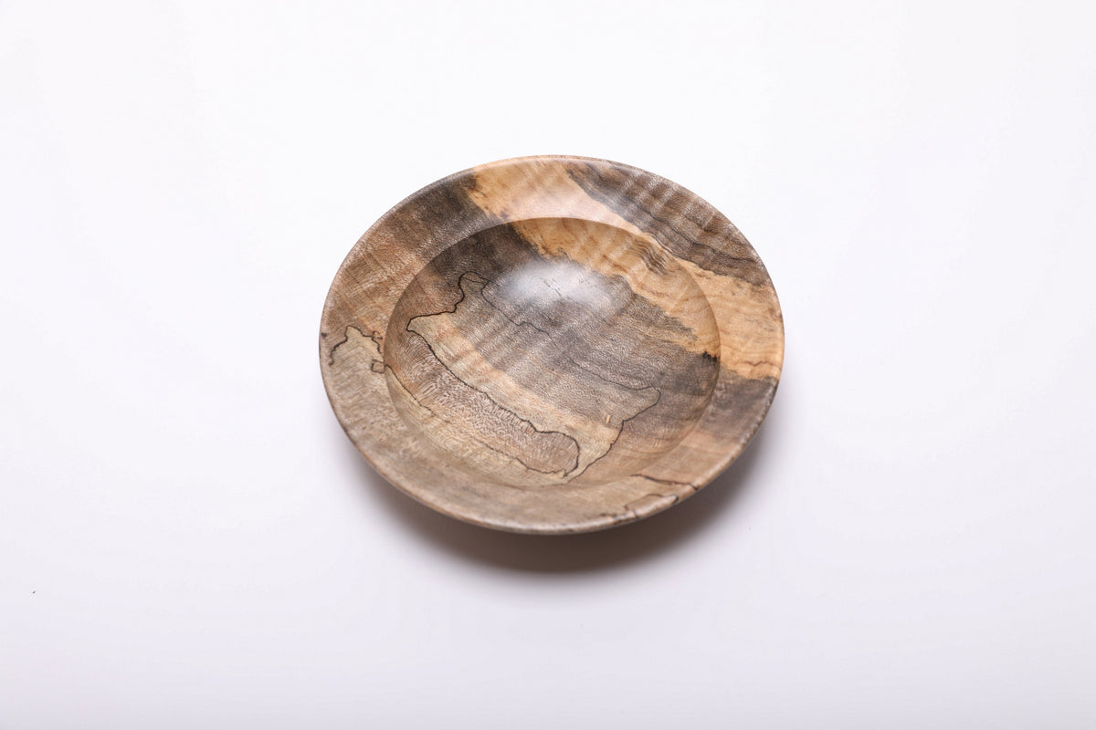 Angled top view of the maple ring dish, highlighting diagonal tiger stripes and black spalting around the shallow interior.