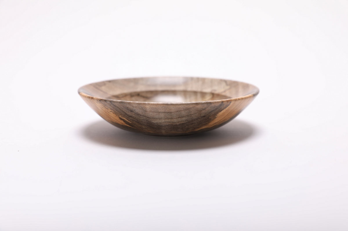 Side view of the spalted tiger maple ring dish, showing its low curved profile, rounded rim and dark striped grain.