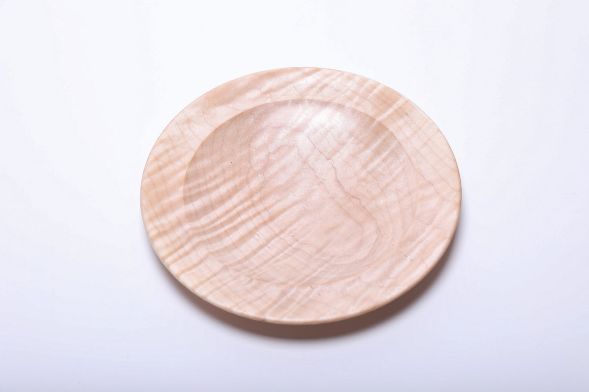Top view of tiger maple wooden dish with diagonal rippling figure across its shallow center and broad rim.