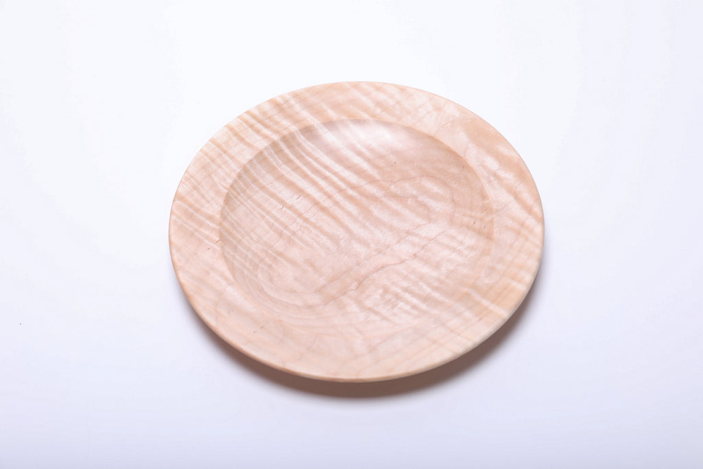 Top view of tiger maple dish with diagonal tiger stripes crossing the recessed center and rounded rim.