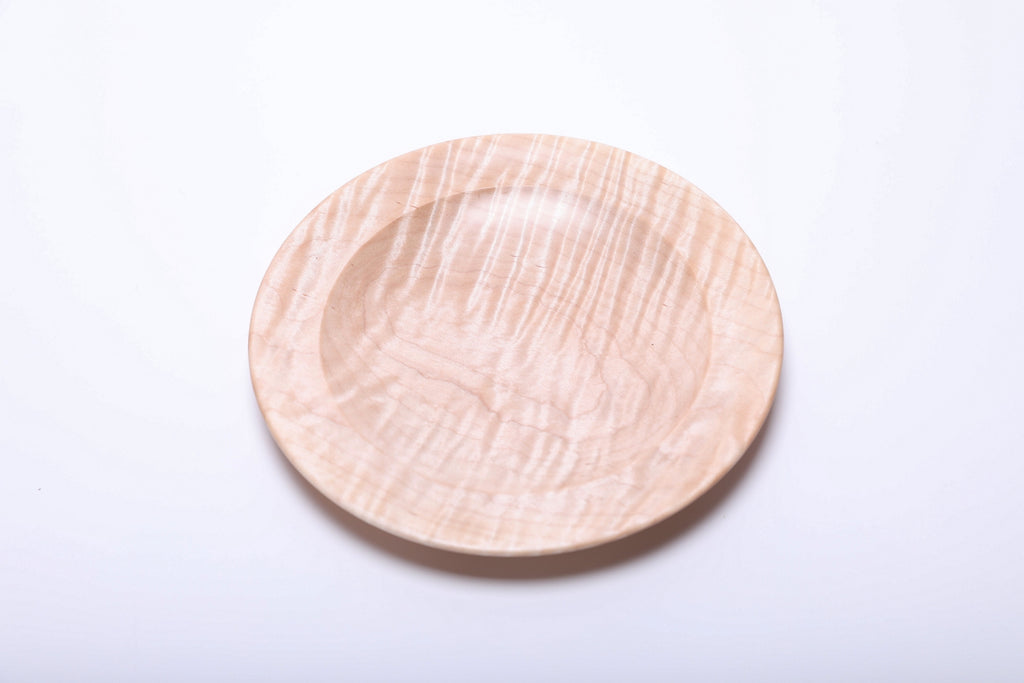 Top view of tiger maple dish showing long rippling grain bands and the gentle curve of its inner rim.