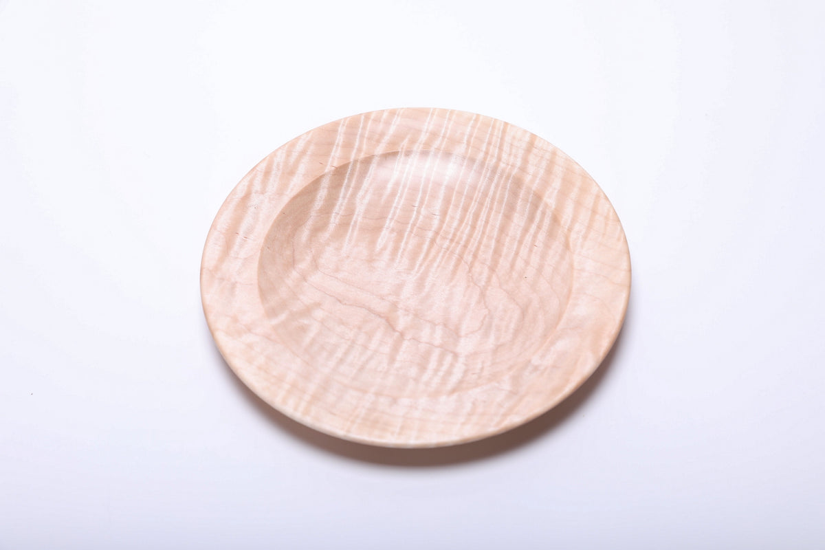 Top view of tiger maple dish showing long rippling grain bands and the gentle curve of its inner rim.