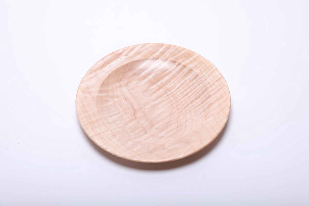 Tiger maple dish rotated to reveal diagonal highlights across its pale wooden surface and shallow center.