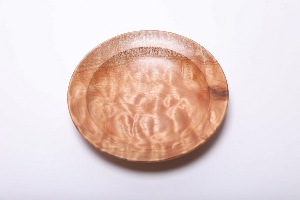 Top view of the quilted maple dish with bright, rippling figure and a dark natural accent along the right rim.