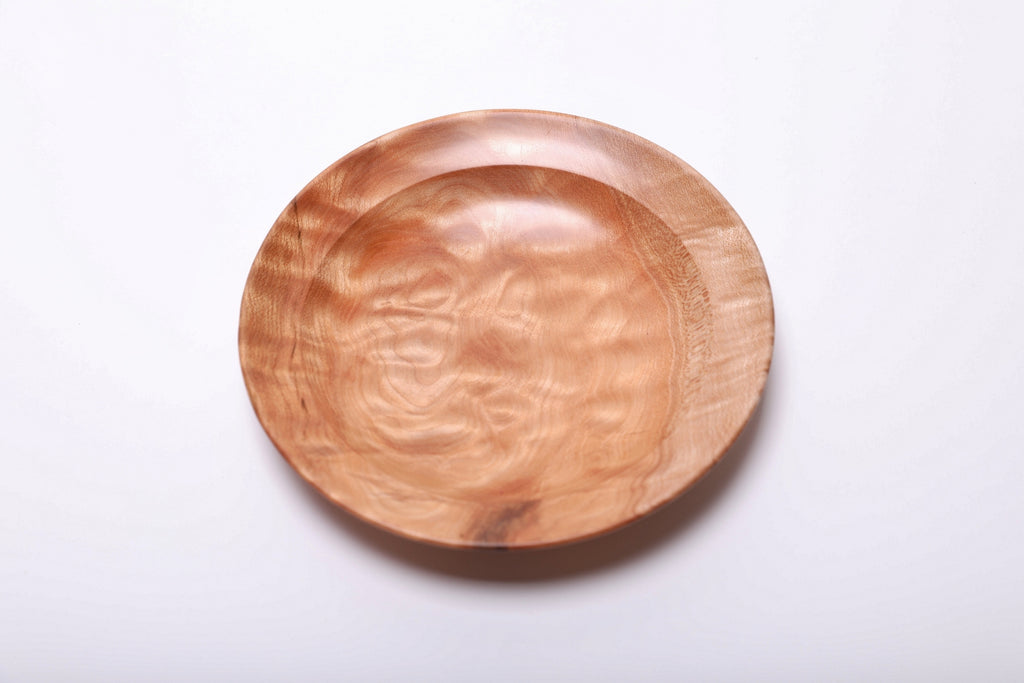 Honey-toned maple ring dish from above, with flowing grain across the interior and a dark streak near the front edge.
