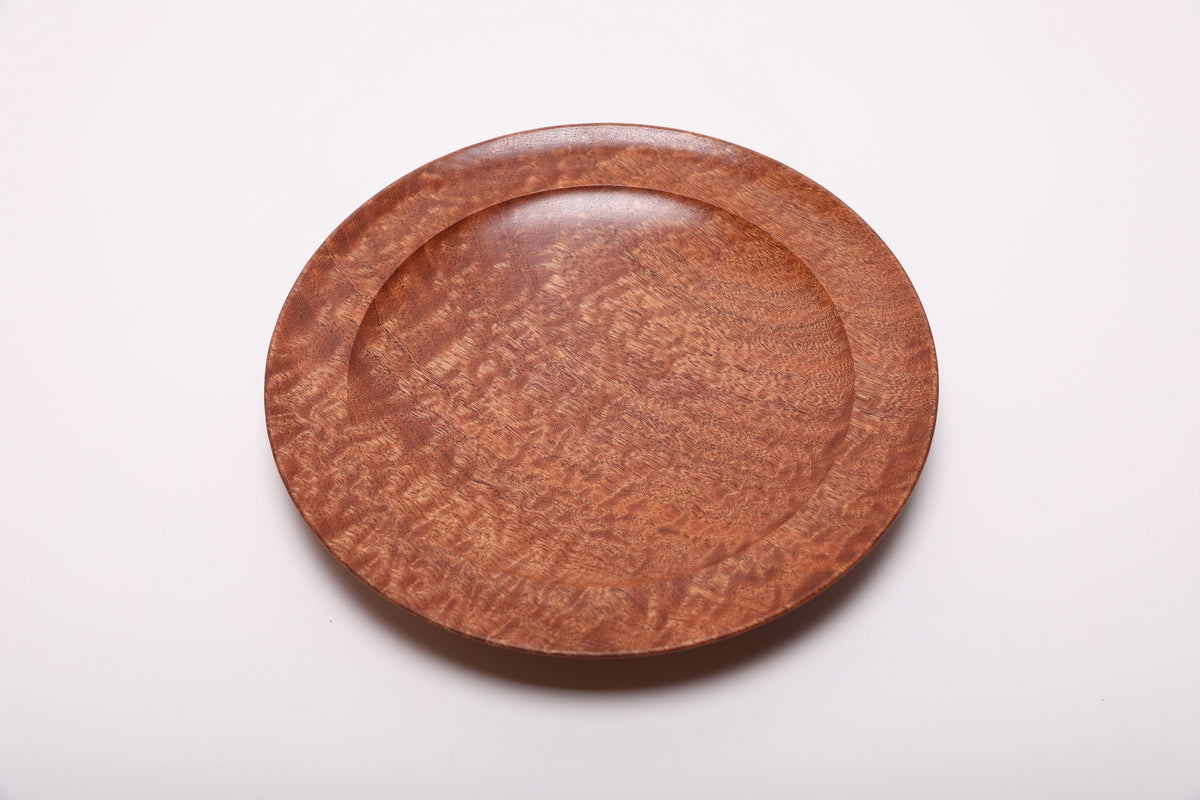 Pommele sapele bowl rotated slightly, showing diagonal bands of shimmering figure across the shallow interior.
