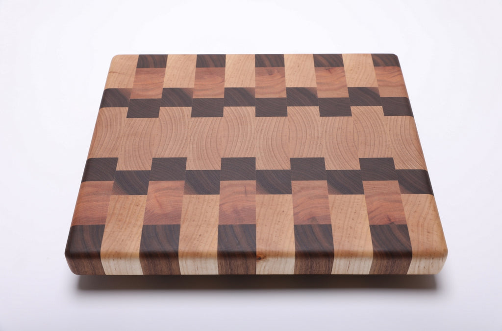 Maple, walnut and cherry end grain cutting board with a wide maple center and interlocking walnut and cherry blocks.