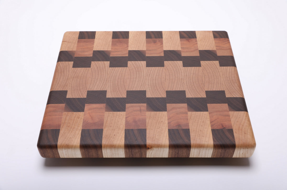 Maple, walnut and cherry end grain cutting board with a wide maple center and interlocking walnut and cherry blocks.