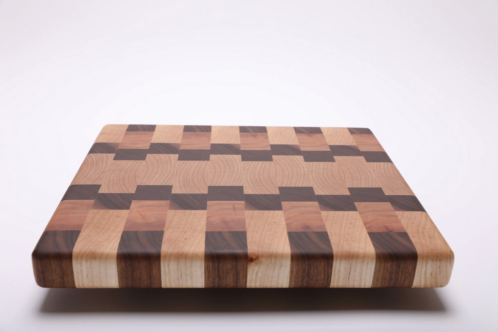 Low angled view of the end grain cutting board showing its thick striped edge and rounded corners.