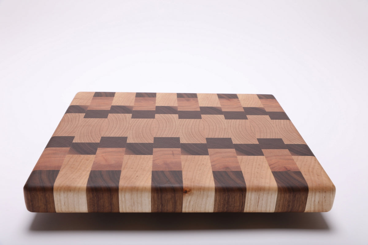 Low angled view of the end grain cutting board showing its thick striped edge and rounded corners.