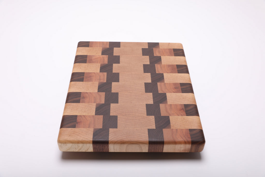 Lengthwise view of the cutting board with a light center bordered by stepped walnut bands and alternating wood blocks.