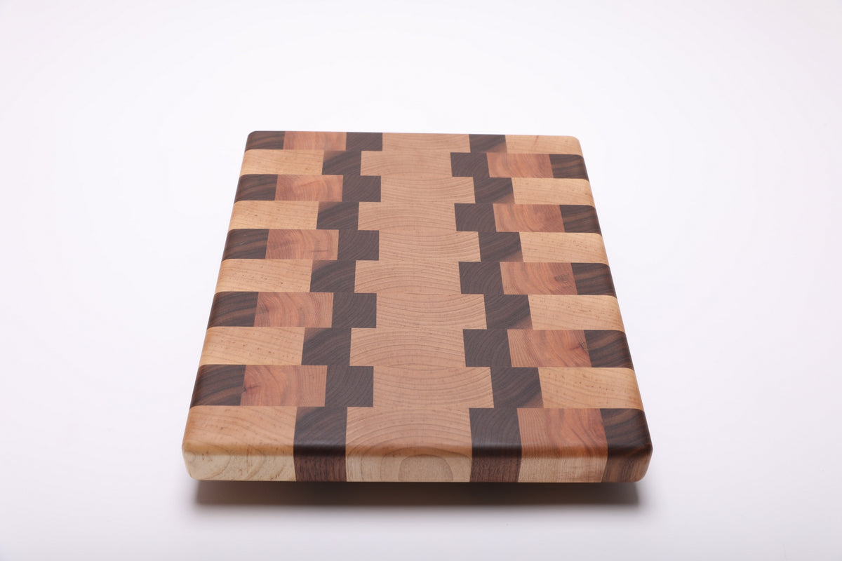Lengthwise view of the cutting board with a light center bordered by stepped walnut bands and alternating wood blocks.