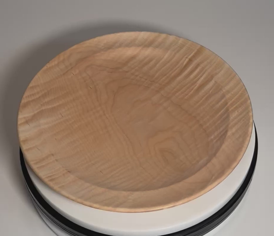 Hand-turned tiger maple wooden platter rotating on display stand, showcasing chatoyant tiger figure shimmer from all angles