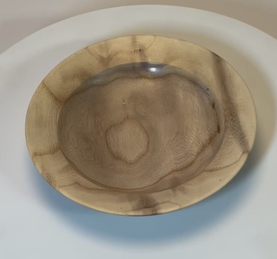 Video of ironwood ring dish rotating to show iridescent amber and cream figure
