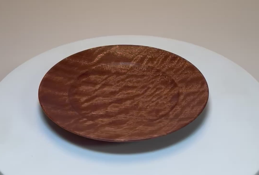 Quilted ribbon sapele wooden ring dish rotating 360° on turntable, showing quilt figure grain, curved taper, undercut rim, and raised foot — handcrafted in NC, USA