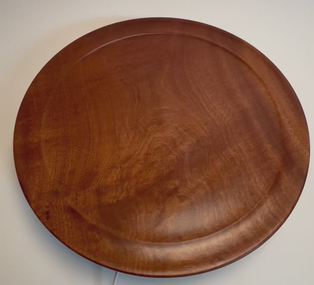 Handcrafted large Khaya African mahogany serving platter rotating on display stand – 360° view of iridescent grain and natural oil finish	