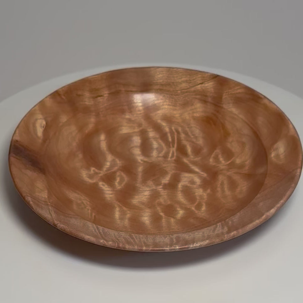 Pillow quilted maple ring dish on a rotating display, showing its shimmering grain, shallow interior, and rounded rim from changing angles.