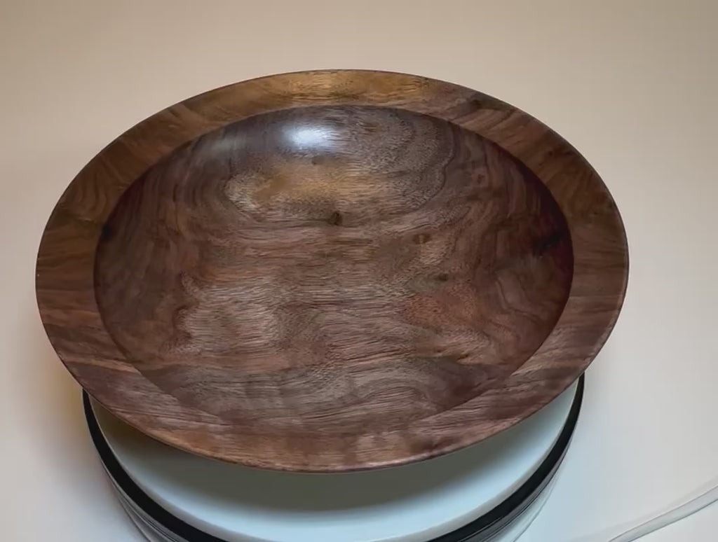 Curly wild black walnut wooden bowl rotating 360 degrees — handcrafted 10-inch diameter by 2.5-inch deep bowl with dramatic curly figure, bud scar halos, undercut rim, raised foot, and food-safe natural oil finish, made in NC by Sanders Woodworking
