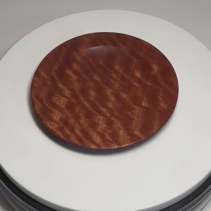 Pommele sapele ring dish rotating on a display, showing its figured grain and curved profile