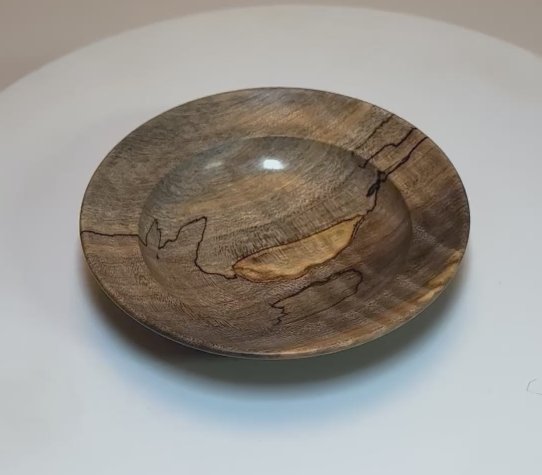 Spalted tiger maple wooden ring dish rotating 360° on turntable, showing gray-to-amber spalting, tiger figure, undercut rim, and raised foot — hand-turned from salvaged firewood in NC, USA