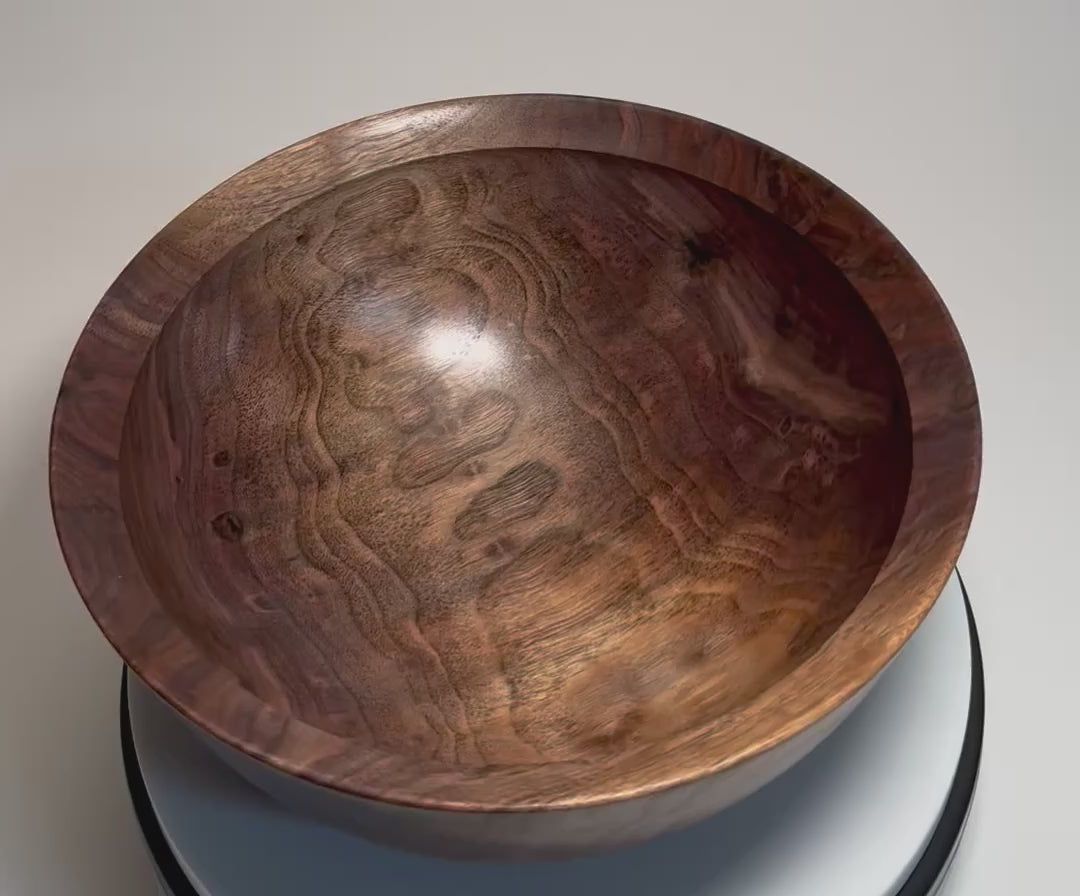 Hand-turned spalted wild black walnut bowl rotating on display stand, showcasing snowman figure, spalted grain, and deep curved form from all angles