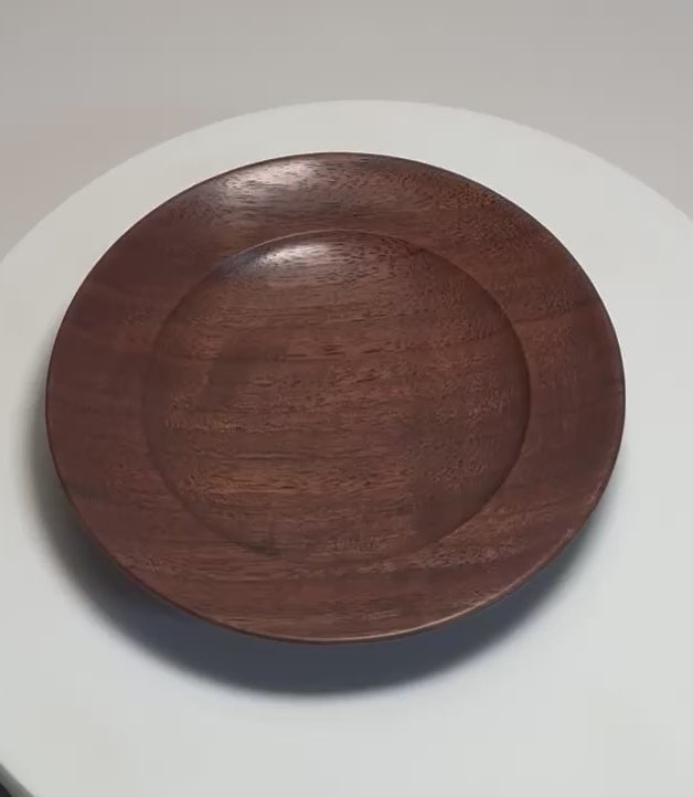 Hand-turned quartersawn black walnut ring dish rotating on display stand, showing grain, profile, and oil finish from all angles