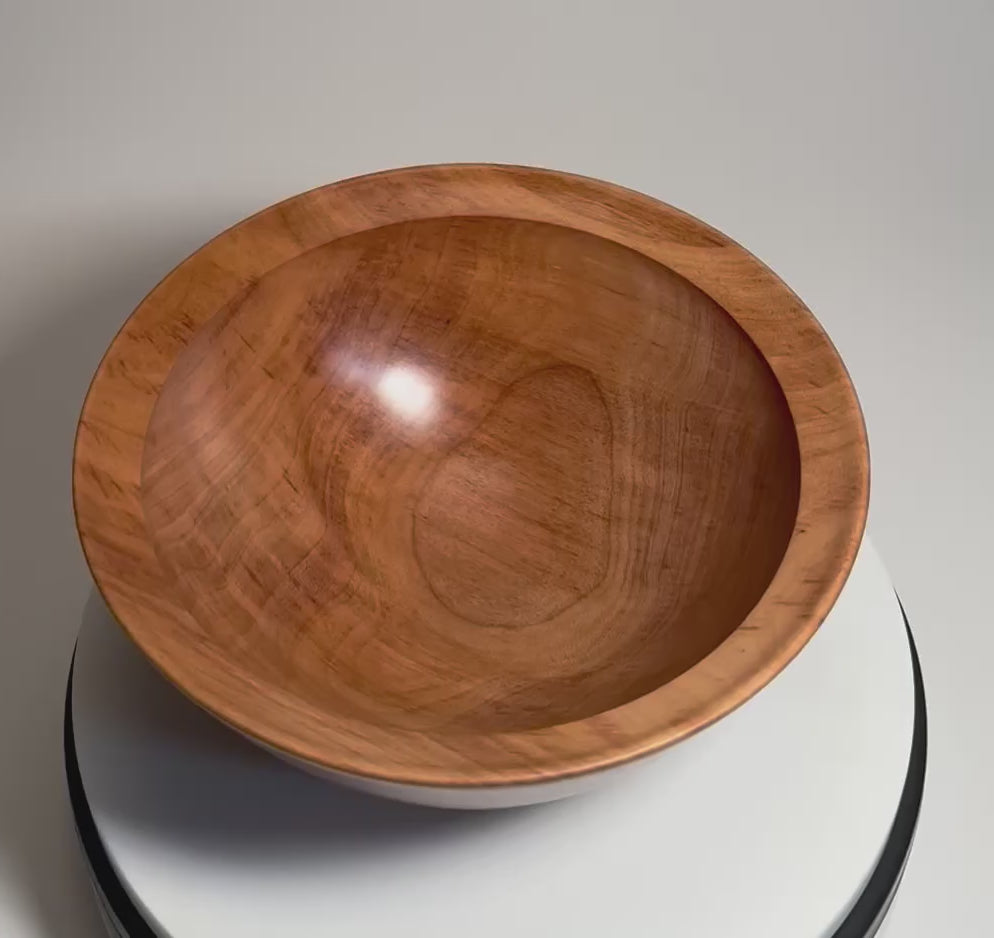River birch wood bowl rotating 360 degrees on display stand, showcasing warm cinnamon tones, amber highlights, iridescent grain, and hand-turned form